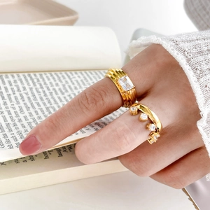 Close-up of elegant gold square zircon rings on finger with soft book background