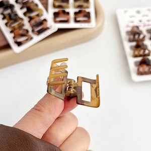 Mini leopard print square claw clip in amber brown resin shown in hand for detail