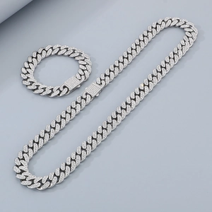 Macro detail of silver stainless steel iced-out Cuban chain necklace and bracelet set