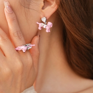 Close-up of a pink poodle jewelry set with earrings and ring featuring crystal details