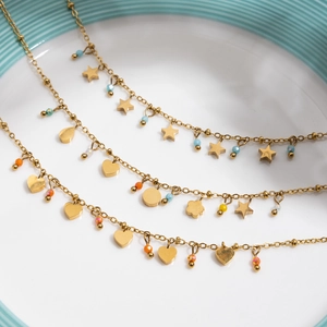 Detail of 18K gold stainless steel layered necklace with orange crystal heart and star charms