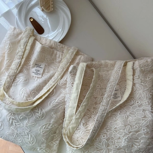 Detailed close-up of beige floral lace embroidery on a vintage style cotton tote bag