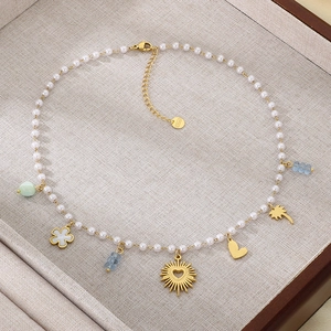 Detail of beaded necklace with gold heart pendants, imitation pearls and tropical charms