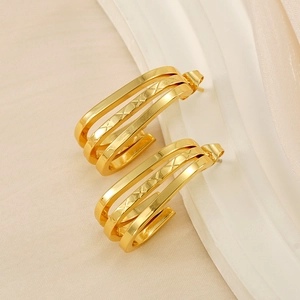 Vista macro dettagliata degli orecchini a tre strati in oro 18K con motivi incisi