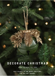 Detail of dark green metal Christmas bell with golden pine needles on tree branches