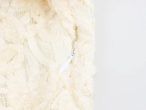 Détail de la texture de dentelle blanche et fermeture éclair invisible sur la robe