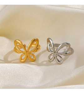 Detailed shot of butterfly open rings in gold and silver over beige silk fabric