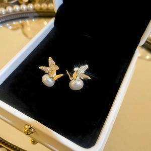 Close-up of golden butterfly pearl earrings with sparkling zircons in a jewelry box