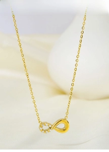 Detailed close-up of gold titanium steel infinity necklace with sparkling zircon inlay