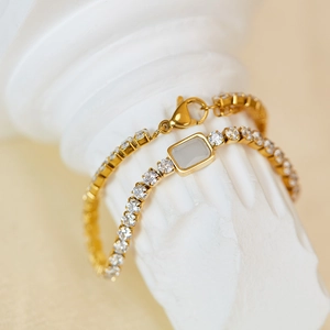 Macro shot of gold-plated bracelet with clear zircon crystals on white plaster column
