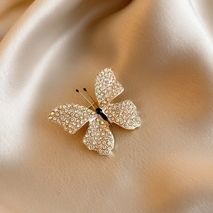 Detailed macro view of 14k gold-plated butterfly brooch with crystals on silk