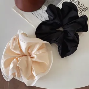 Set of premium French satin scrunchies in classic black and beige on a stylish desk setup