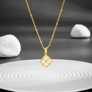 Titanium steel necklace with white shell clover pendant and gold star on a rippled plate