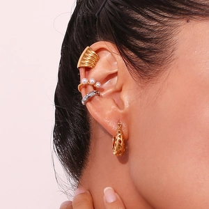 Detailed look at layered gold teardrop heart earrings with pearl cuff accents