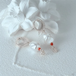 Detail of twisted silver hoop earrings with baroque pearl and red bead accent