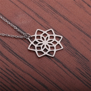 Vue macro d'un pendentif lotus évidé en acier inoxydable argenté sur bois