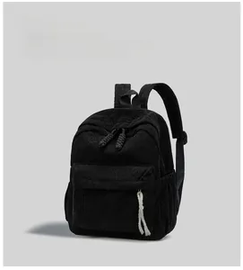 Detail of black corduroy backpack showing thick texture and woven zipper puller accent