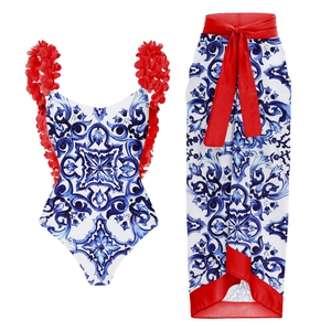 Detail of blue majolica print swimsuit and red floral sarong set on white background