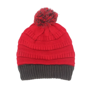 Détail du bonnet en tricot bicolore avec couronne rouge et pompon gris décoratif