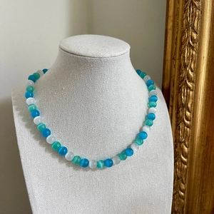 Close-up of glacier blue cat eye stone beads and elegant heart pendant necklace