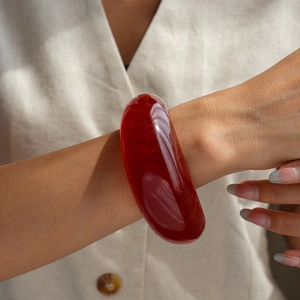 Detail of a vintage red translucent resin round bangle worn on a female wrist