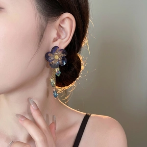 Floral crystal tassel drop earrings featuring dark resin flower and gold chain on model