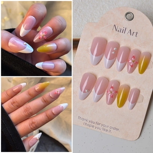 Detail showing 3D floral accents and yellow gradient on almond shape press-on nails