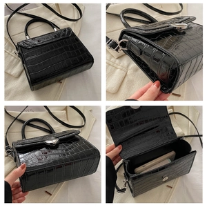 Detail of black crocodile texture faux leather bag with silver metal lock closure