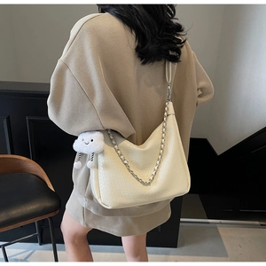Detail of white woven PU leather bag with silver chain strap and cloud plush pendant