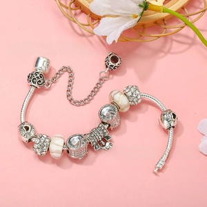Detail of silver-plated snake chain bracelet featuring heart charms and crystal beads