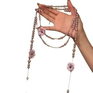 Lavendelfarbene Perlenkette mit lila Stoffblumen für einen eleganten Strandurlaub-Stil.
