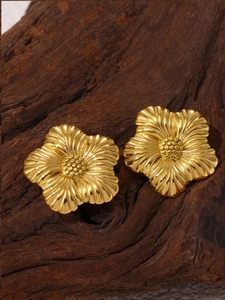 Detailed close-up of golden vintage floral earrings displayed on a dark wooden block