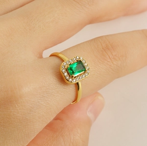 Close-up of gold stainless steel ring featuring emerald-cut green zircon and pave crystals