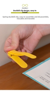 Detail of yellow silicone bookmark clip with durable spring mechanism on a book page