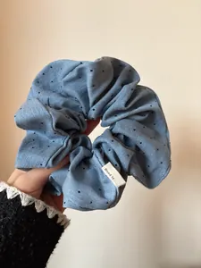 Close-up of light blue polka dot scrunchie with a handmade tag and soft fabric texture