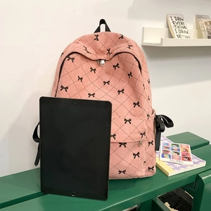 Pink corduroy backpack with bow prints shown next to a tablet for size reference