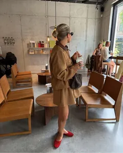 Detailansicht von khakifarbenem Workwear-Jacken und Minirock-Set mit roten Ballerinas