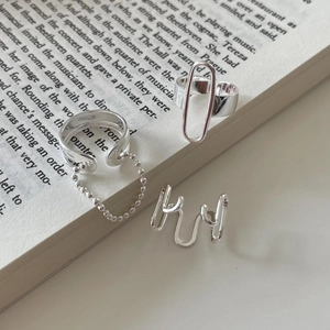 Minimalist 925 sterling silver geometric rings with chain and wave patterns on a book