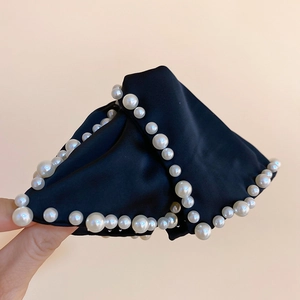 Détail de la pince à cheveux en satin noir avec bordure en perles et texture soyeuse