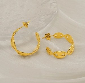 Detail of C-shaped golden pig nose earrings on silk and glass tray for a luxury look