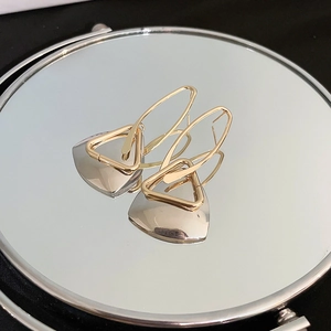 Macro shot of geometric earrings featuring gold triangles and silver trapezoid plates