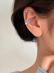 Close-up showing a silver cat paw ear cuff clip worn on the upper ear cartilage