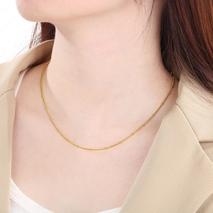 Detail of adjustable gold snake chain necklace with beads worn with a beige blazer
