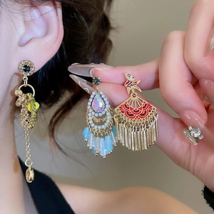 Macro shot of ethnic style earrings with fan tassels, blue beads, and gold chain details