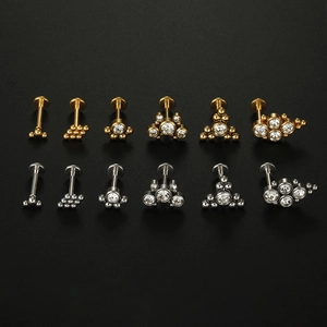 Detailed set of stainless steel lip and ear studs with shiny zircon stones on black background
