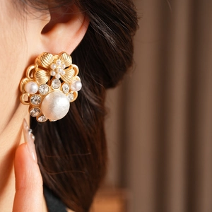 Detaillierte Nahaufnahme vintage goldener Blumenohrstecker mit großer Perle und Kristallen
