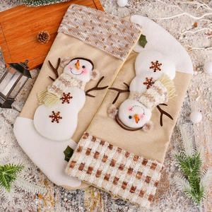 Calze di Natale in lino con pupazzo di neve su un tavolo festivo con pigne e decorazioni