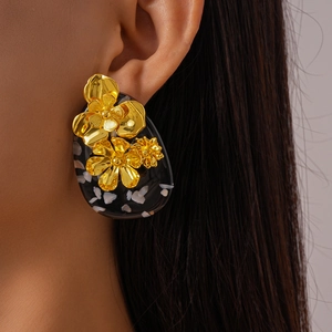 Close-up of vintage resin oval earring with gold flower details on a model's ear