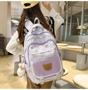 Detail of purple plaid school backpack with cute bear patch and plush rabbit charm