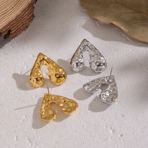 Gehämmerte Herzohrstecker aus Edelstahl in Gold und Silber auf Steinuntergrund